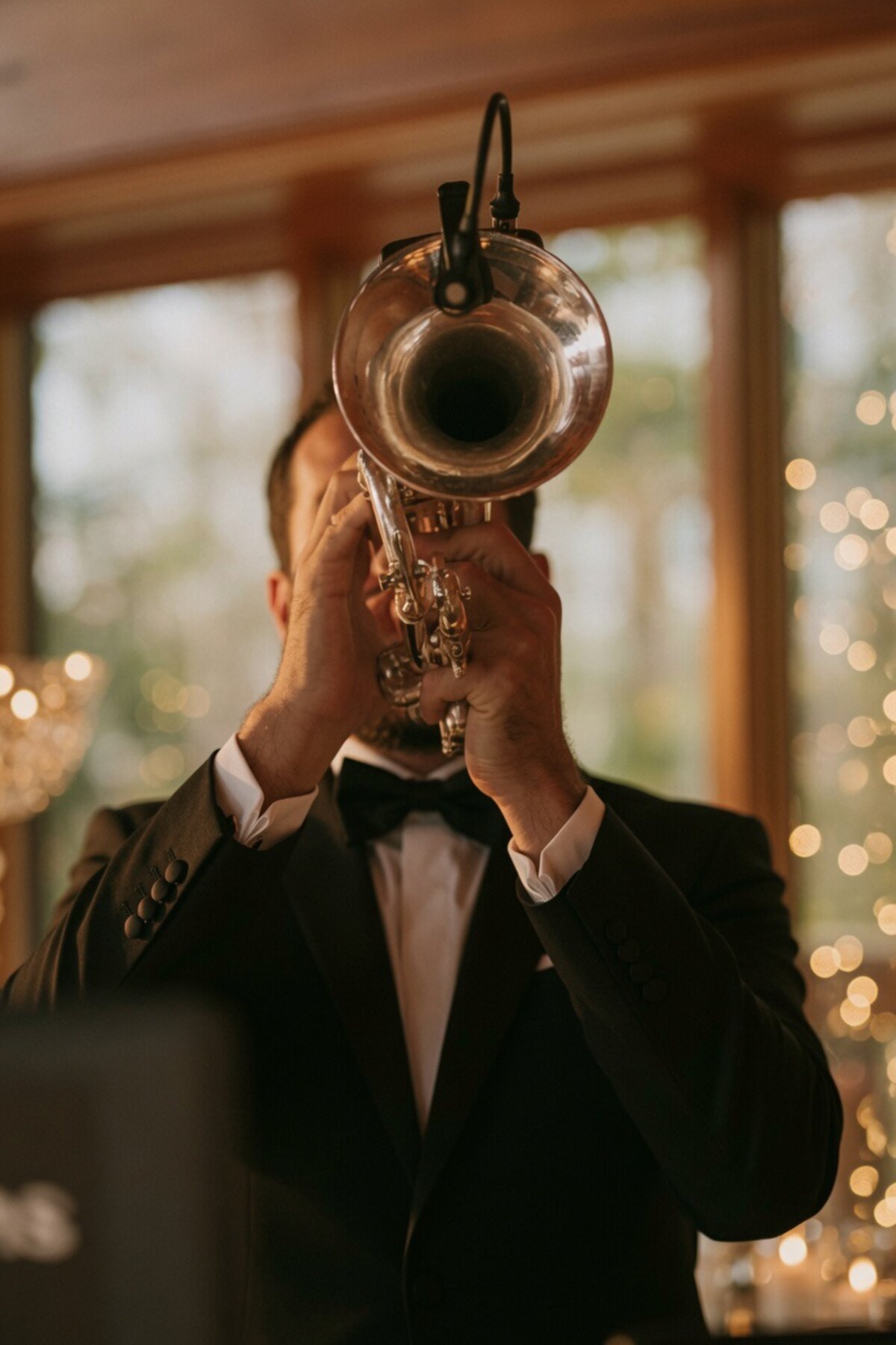 Close-up of DJ Glaze's trumpet bell with string-light bokeh at a wedding reception